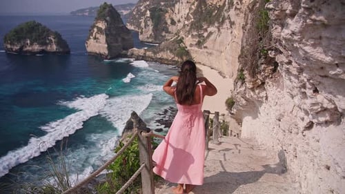 Frau im rosa Kleid genießt die malerische Aussicht am Diamond Beach Nusa Penida