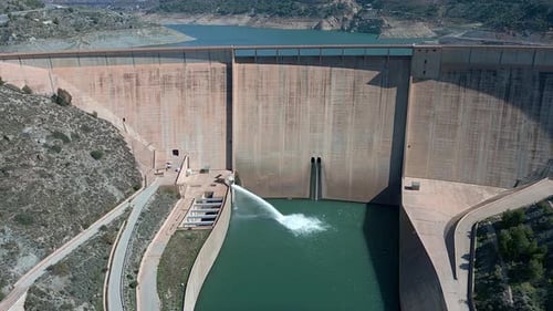 Dam and water reservoir. Panoramic aerial view of the dam and hydroelectric plant rising. Dolly out.