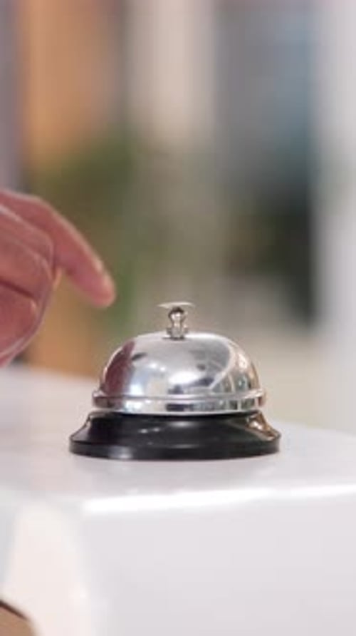 Hand, desk and person with bell in hotel for help, concierge and customer service alert