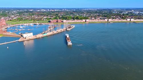 Flying closer to the port on Lake Markemeer. Ferry moves to the berth. Panorama of Lelystad