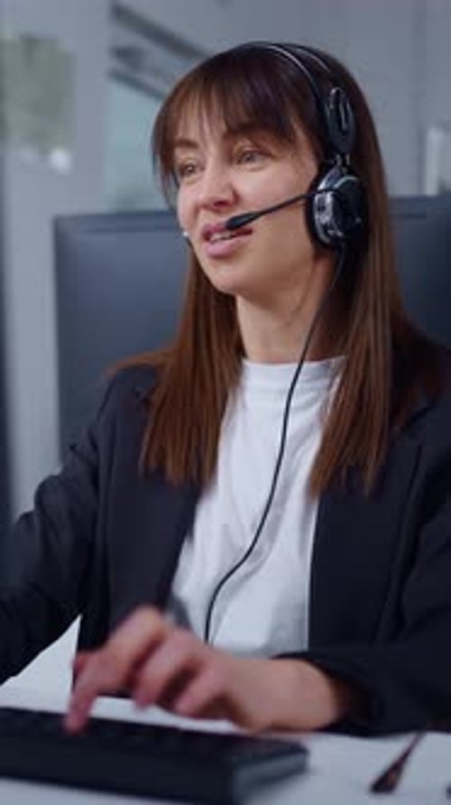 Focused Female Customer Support Agent Wearing Headset and Working on Computer in Modern Office