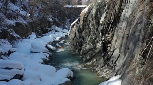 Wunderschöner Fluss in den Bergen mit hohen Klippen und viel Schnee, Luftaufnahmen in 4k