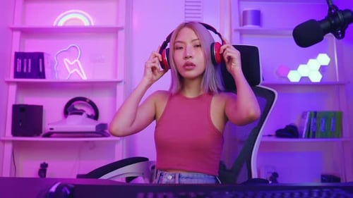 Young Adult Puts on Headphones in Neon Gaming Room