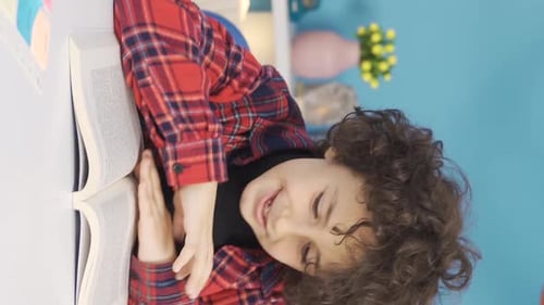 Vertical Video of Successful and smart male primary school student reading a book, doing homework.