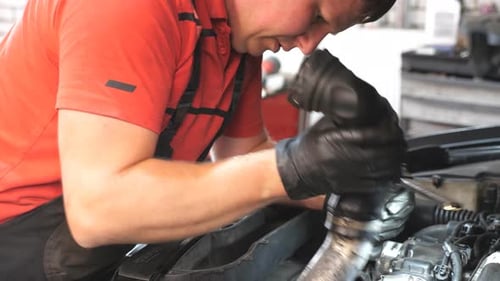 Professional Auto Mechanic Works Under Hood of Vehicle Repairman Fixing Engine of a Car at Workshop