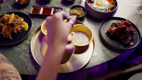 close-up of a girl pouring a traditional Korean low-alcohol drink from a golden teapot into a cup