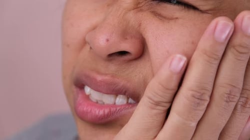Close-up of woman having toothache and her hands touching her face.