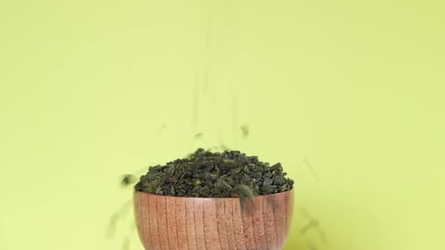 Black Dry Tea Pouring in a Bowl Pile of Mix Black and Green Tea Leaves Close Up Macro Front View