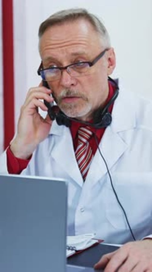 Doctor Talking on Phone While Using Laptop
