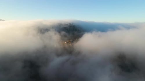 Aerial View of Moody Landscape Above Foggy Forest with Pine Trees Covering Mountain Hills at Sunset