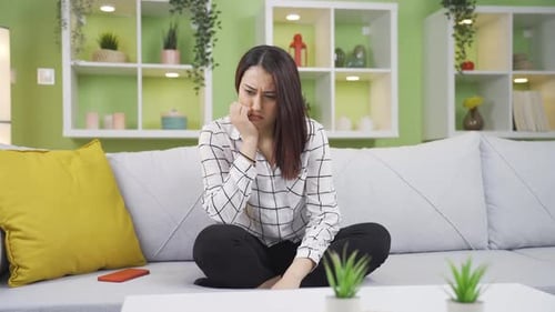 Worried Young Adult Woman Sitting on Couch