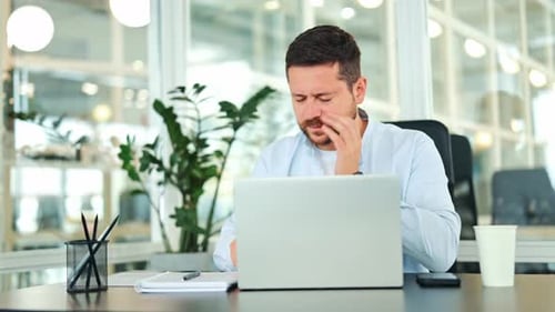Stressed Businessman Experiences Headache at Office Desk