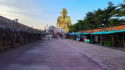 4k Panning forward to an Elephant statue and The biggest golden statue of a buddhist monk Luang Pu T