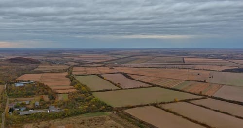 Aerial View of Expansive Agricultural Fields Under a Cloudy Sky in Rural Landscape