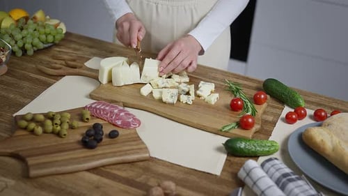 Woman cuts cheese for appetizer in bright kitchen