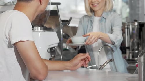 Friendly Barista Serving Coffee to Customer in Cafe