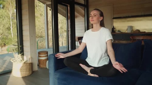 Woman Meditates on Couch in Sunny Modern Home