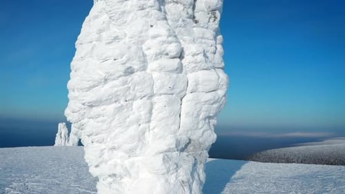 Snowy landscape on a hill with frozen ice stones and blue sky overhead