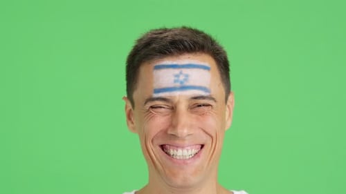 Man Smiles Brightly With Painted Design on Forehead