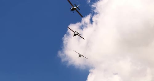 Klassische leichte Propellerflugzeuge fliegen an einem sonnigen blauen Himmel mit weißen Wolken