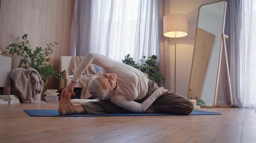 Senior Woman Stretching on Yoga Mat at Home