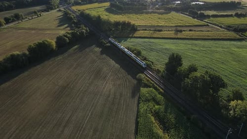 Personenzug fährt im Sonnenlicht durch ländliche Landschaft