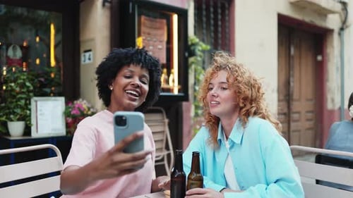 Smiling Women Taking Selfie at Outdoor Cafe