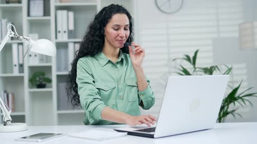 Woman Wearing Headset Typing on Laptop in Office
