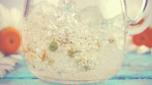Pouring Water into Teapot with Chamomile Flowers