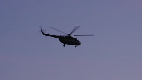 Dark Silhouette of a Helicopter Flying Across a Purple Dusk Sky