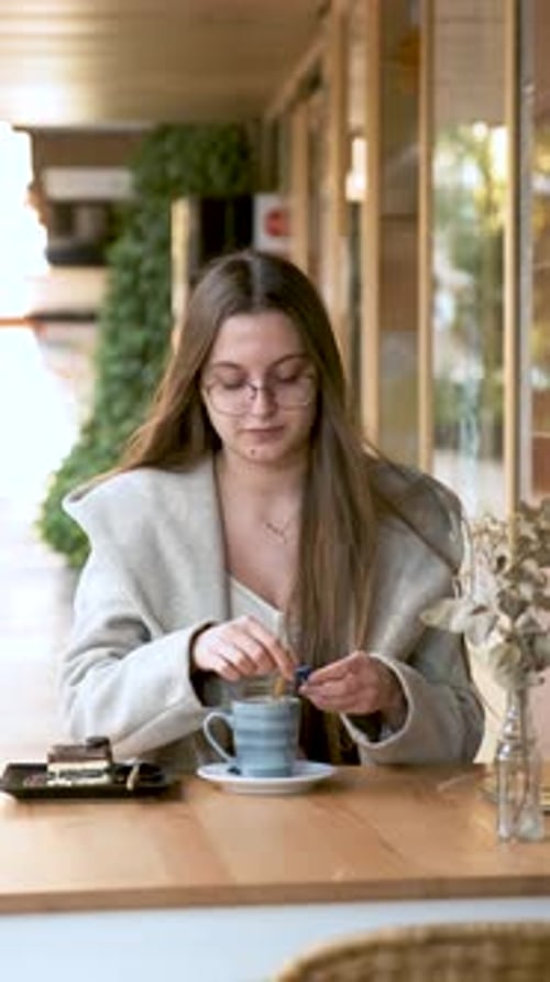 Woman Adding Sugar to the Coffee in a Cafe