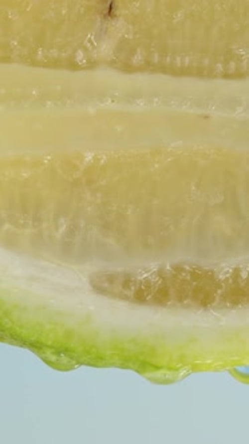 A half of a green lemon against a blue sky, drops of water are flowing down it. Vertical, Social Med