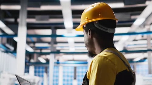 Ingénieur utilisant un ordinateur portable pour surveiller les chaînes de montage d'usines de panneaux solaires