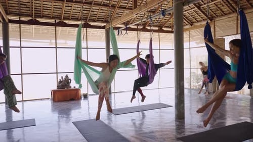 People Practice Aerial Yoga Inside a Studio