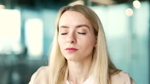 Close up. Young businesswoman relaxing with her eyes closed in a modern office. Portrait of a calm