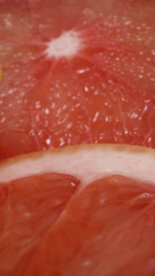 Vertical. Round Slices of Red Grapefruit Are Laid Out on the Table. Dolly slider extreme close-up.