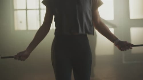 Woman Jumps Rope with Group in Smoky Gym