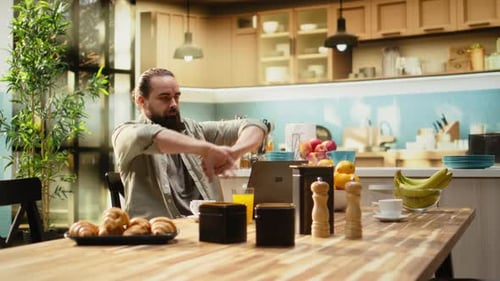 Man Working on Laptop at Kitchen Table with Breakfast
