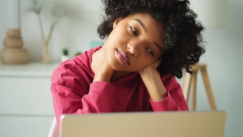 African American Woman Sitting at Table Stretching Massaging Neck Taking Break From Work on Laptop