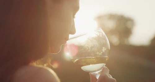 Authentic shot of happy young elegantly dressed woman is tasting a flavor and drinking a white win