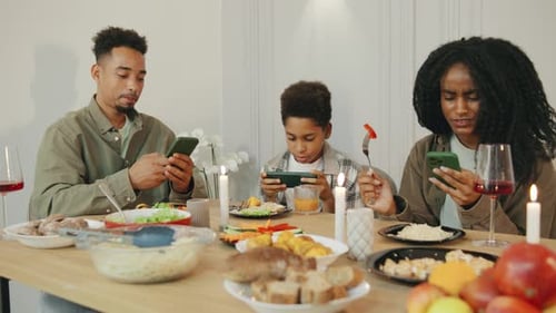 Family Using Smartphones at Dinner Table