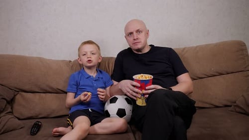Father and Son Watching Soccer Game at Home