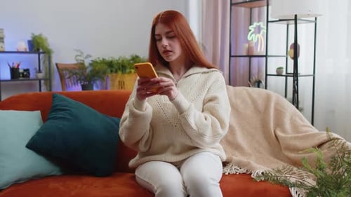 Woman Using Mobile Phone Relaxing on Couch at Home