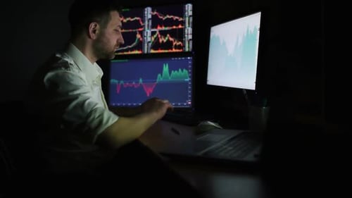 Man Works Late at Night Analyzing Financial Data