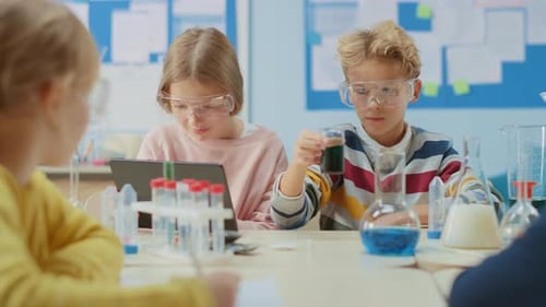 Elementary School Science Classroom: Smart Boy Mixes Chemicals in Beakers and Cute Girl Writes Down