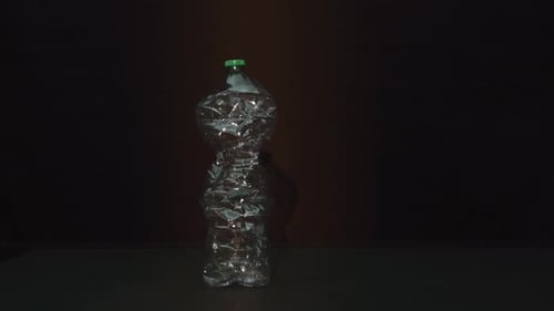 Rotating Crushed Plastic Bottle on Dark Background