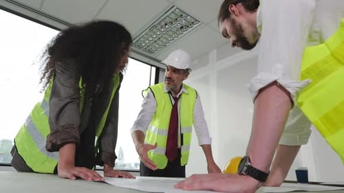 Architects Reviewing Blueprints in Bright Office