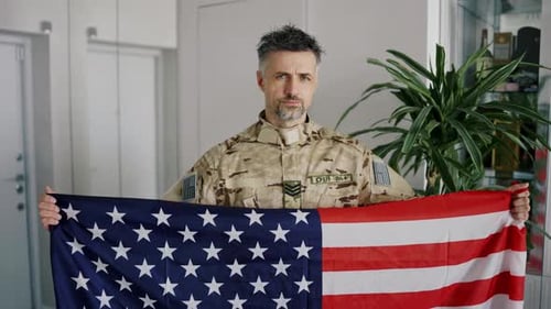 Man in Uniform Holding American Flag Indoors