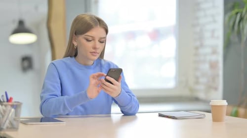 Woman Browsing Internet on Smartphone in Office