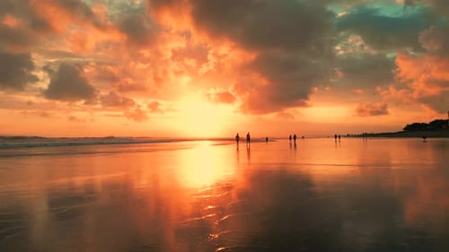 Aerial View of a Stunning Bali Sunset Over a Tranquil Beach with Reflected Clouds and Silhouettes of